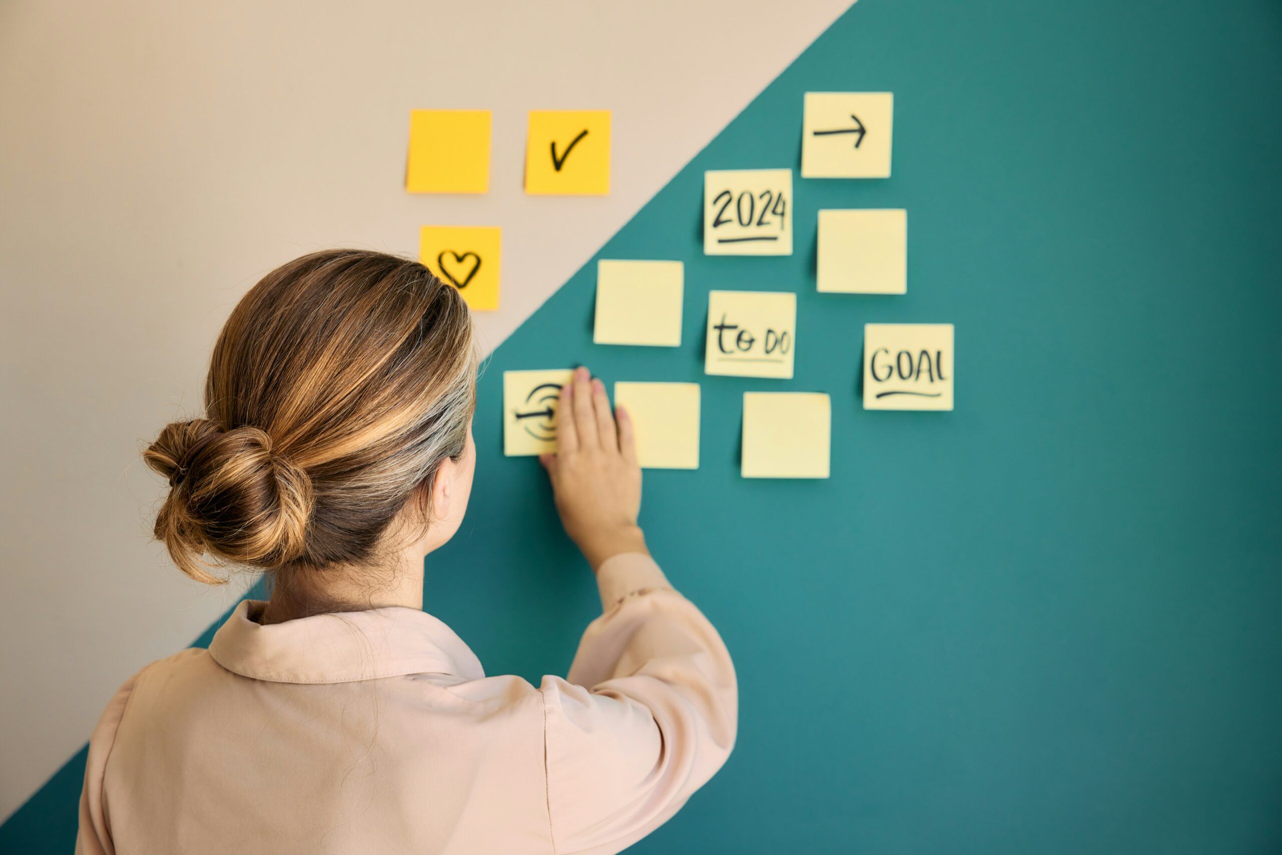 Administrative professional posting inspirational post it notes on the office wall.